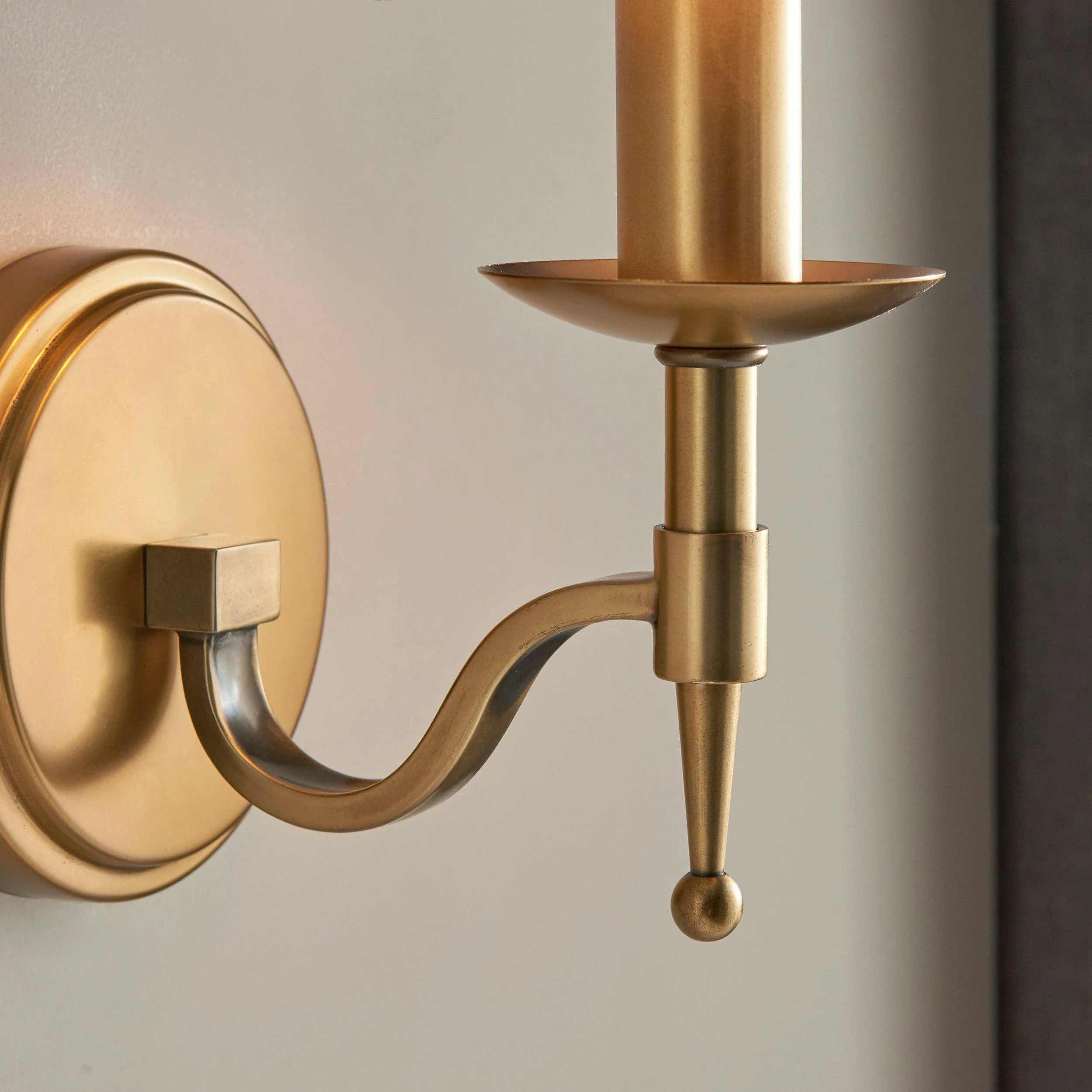 Close view of Tela curved brass arm and candle cup detail