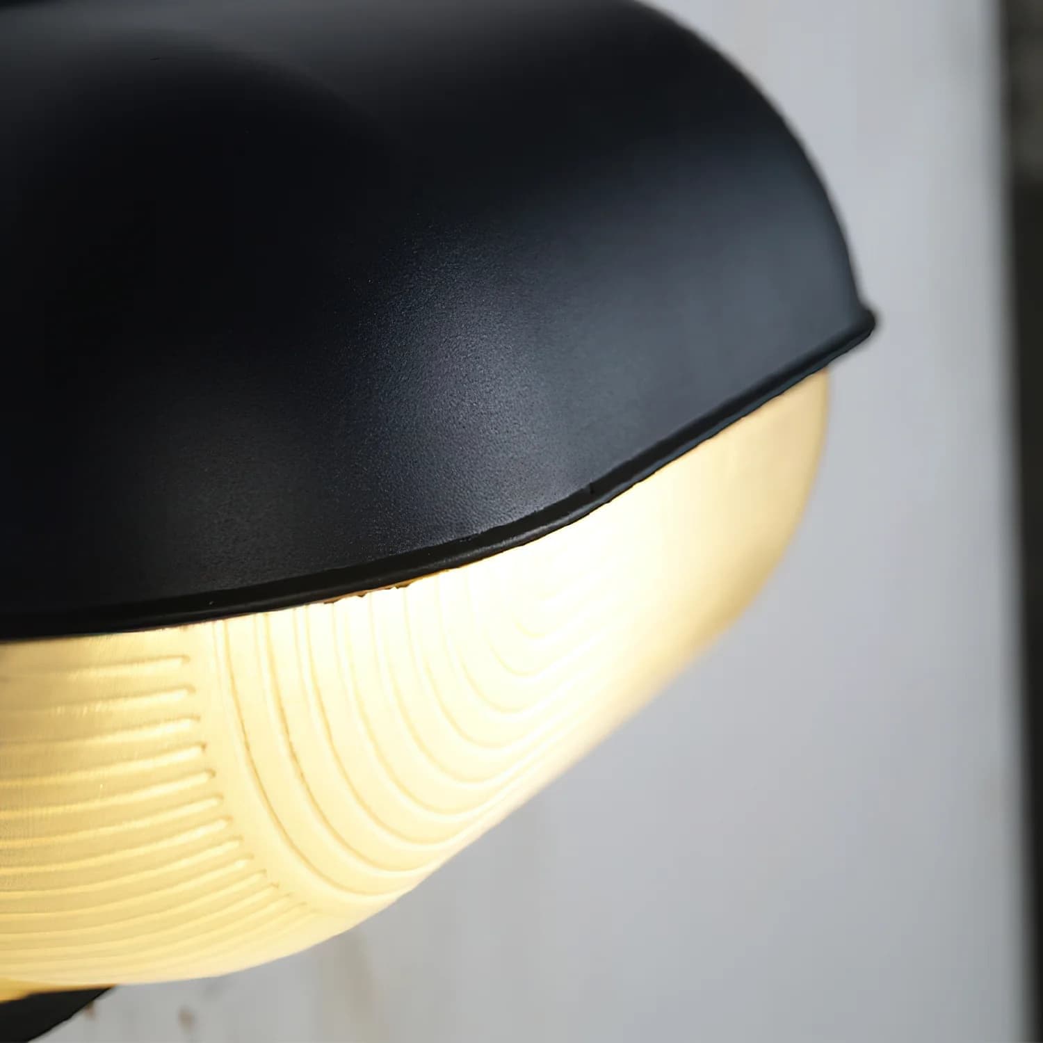 Close-up of the black Docka wall light illuminated