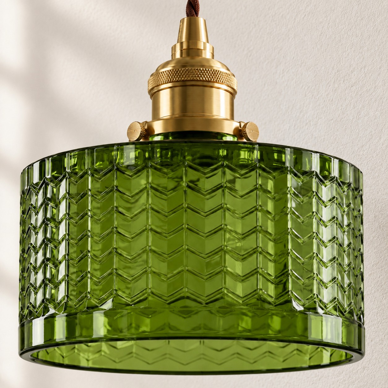 Gros plan de l'abat-jour complet en verre à chevrons vert olive et de la douille en laiton